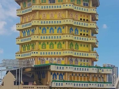 Kuil bergaya pagoda bertingkat dengan fasad kuning dan hijau di bawah langit biru.