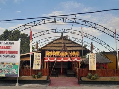 Gerbang masuk suatu bangunan Indonesia dengan elemen arsitektur tradisional dan spanduk penyambutan.
